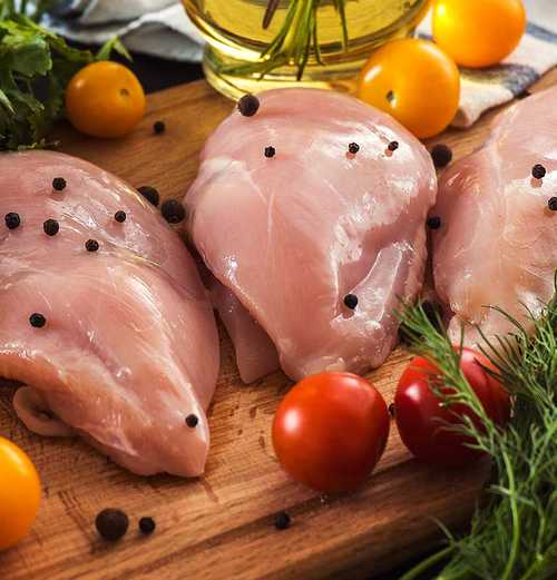 3 pieces of raw chicken on a cutting board