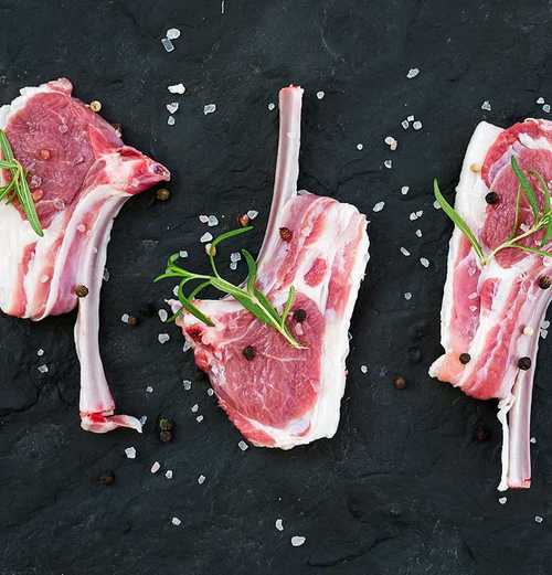 four pieces of raw lamb meat on a stone cuttingboard