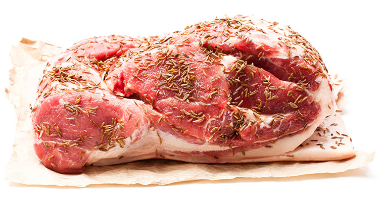 A pork shoulder on wrapping paper, covered in herbs and spices